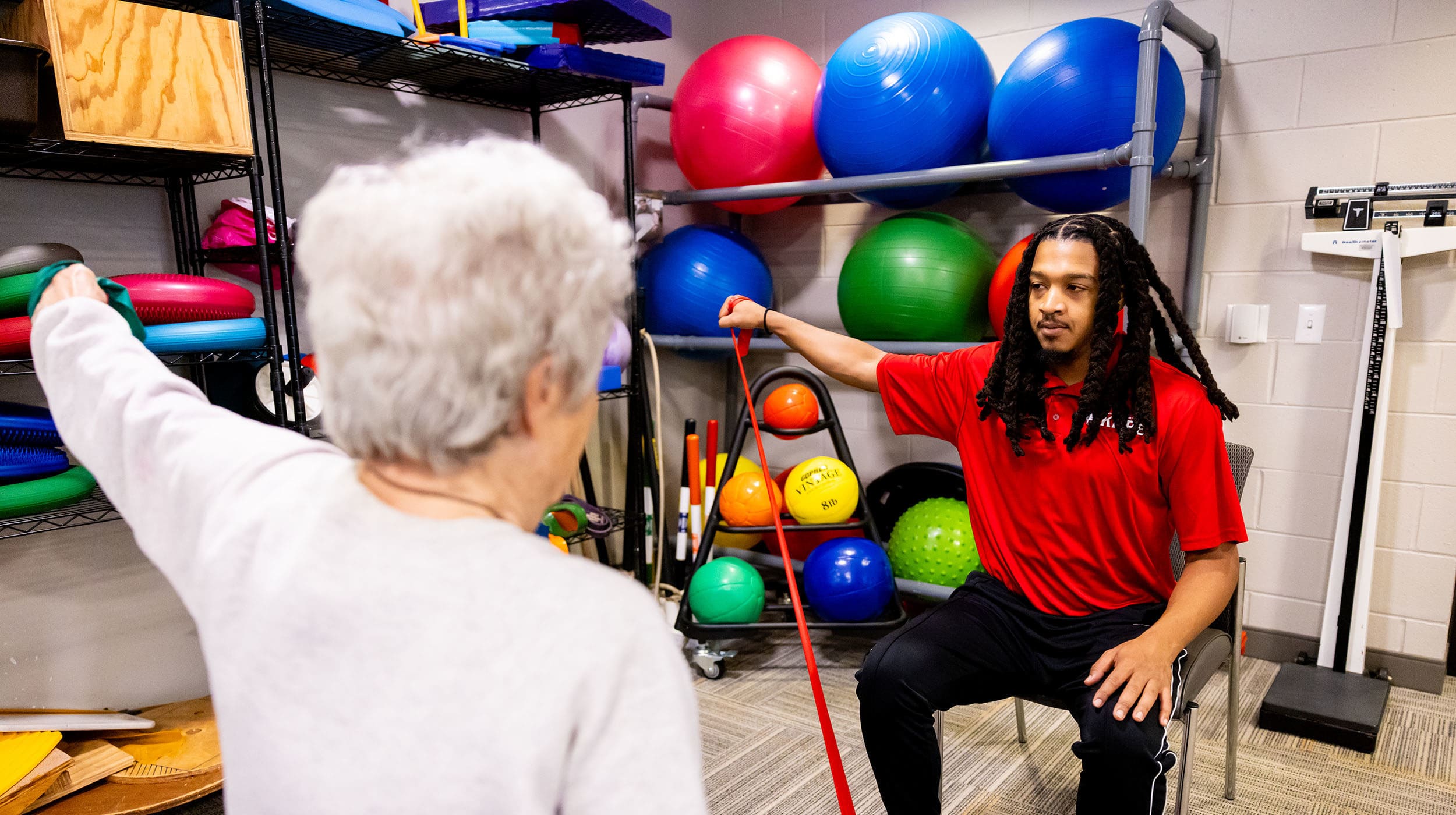 NIU kinesiology student working with a patient on arm stretching exercises with bands