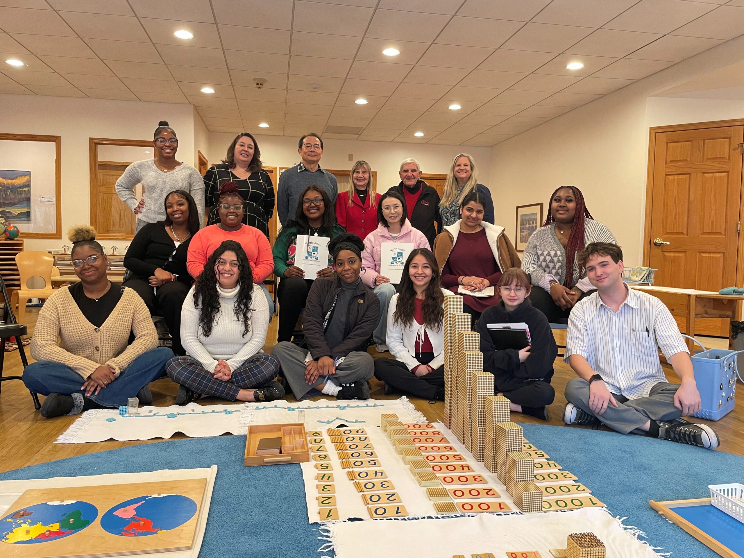 Large group of NIU College of Education students pose for a photo in a classroom.